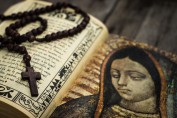 A Religious concept of a rosary and a bible on wood background